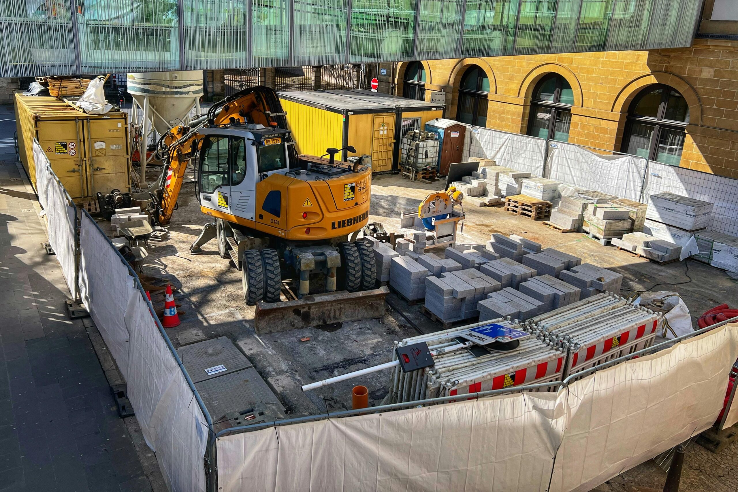 A construction site with machinery and materials in an urban setting during daytime.